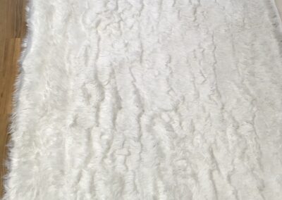 White shag rug on a wooden floor, appearing clean and fluffy after pet odor removal.