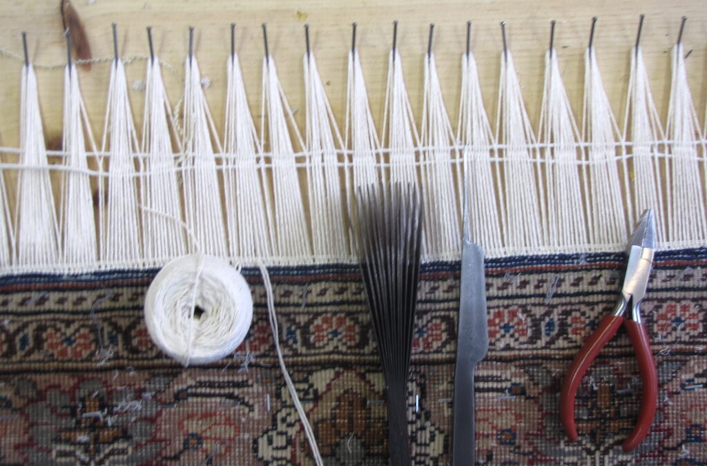 "Rug fringe repair work in progress with tools and new fringe being added on a handmade rug."